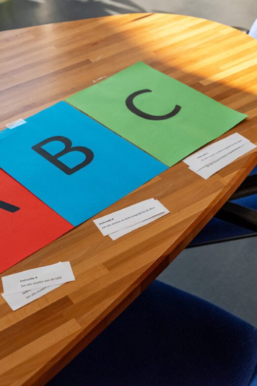 Drie stapels gekleurde kaarten met de letters A, B en C liggen op een tafel; bij elke stapel hoort een eigen opdracht.